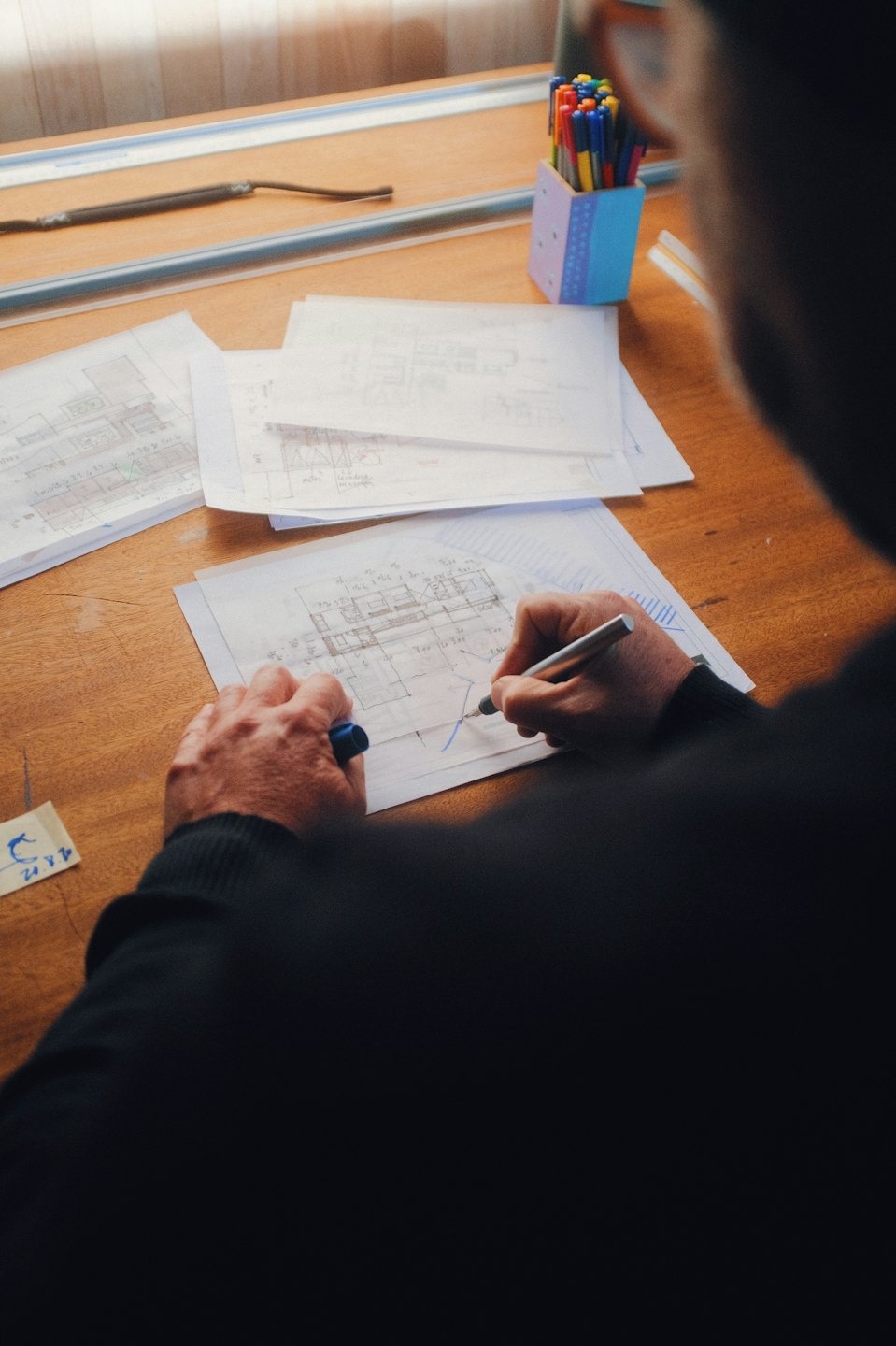 Persona dibujando planos arquitectónicos en una mesa de dibujo.
